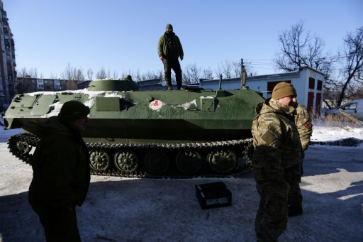 Un auxiliaire sanitaire se tient debout sur un véhicule blindé de transport de troupes le 30 janvier 2017 à Donetsk après avoir déposé un militaire blessé à l’hôpital d’Avdiivka