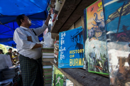 Un homme consulte des livres d’histoire de la Birmanie présentés sur un étal le 7 janvier 2017 dans une rue de Rangoun, en Birmanie