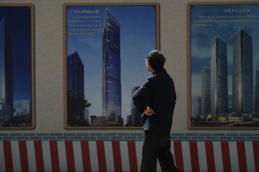 Un homme regarde une affiche devant un site en construction à Pékin