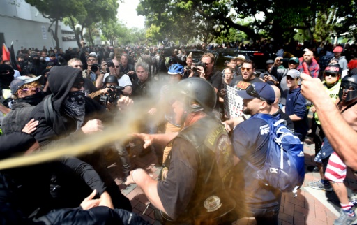 Un homme est aspergé de gaz irritant, lors d’affrontements entre manifestants favorables et opposés à la politique de Donald Trump