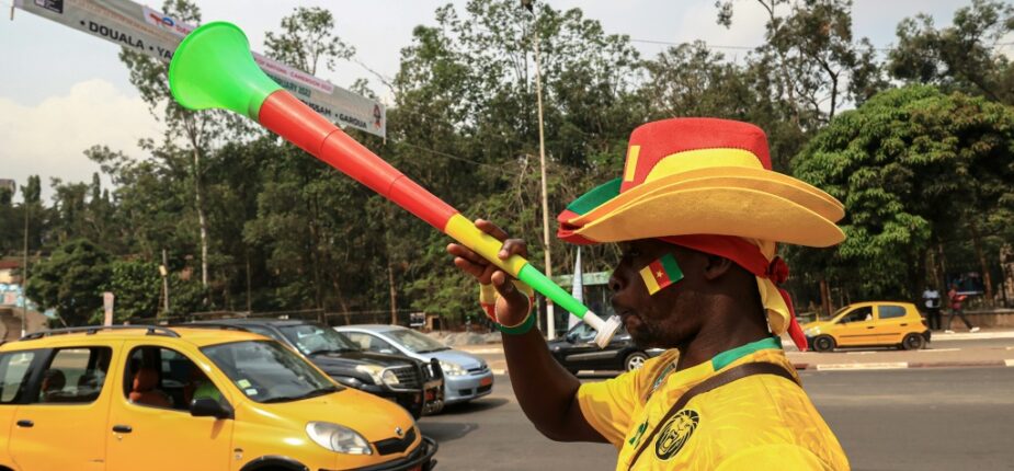 Un vendeur camerounais souffle dans une vuvuzela aux couluers de la sélection nationale de foot à Yaoundé, le 5 janvier 2022