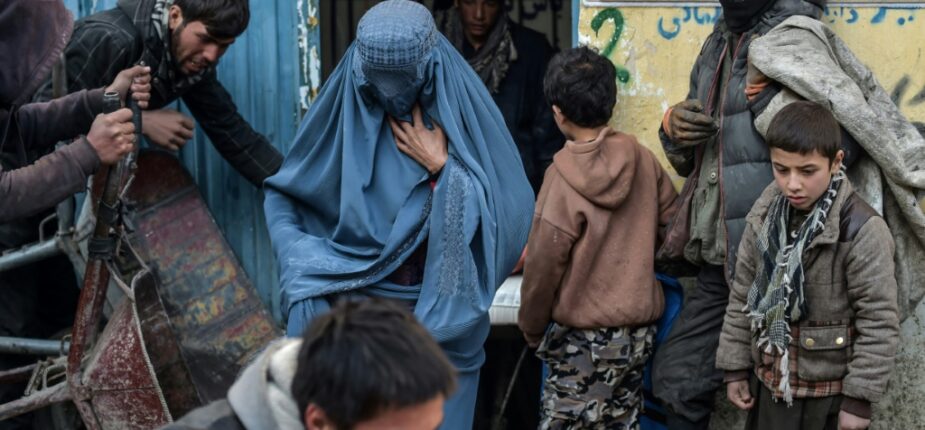 Des habitants font la queue pour recevoir de l'aide humanitaire devant le bureau d'une organisation caritative, le 30 janvier 2022 dans la banlieue de Kaboul