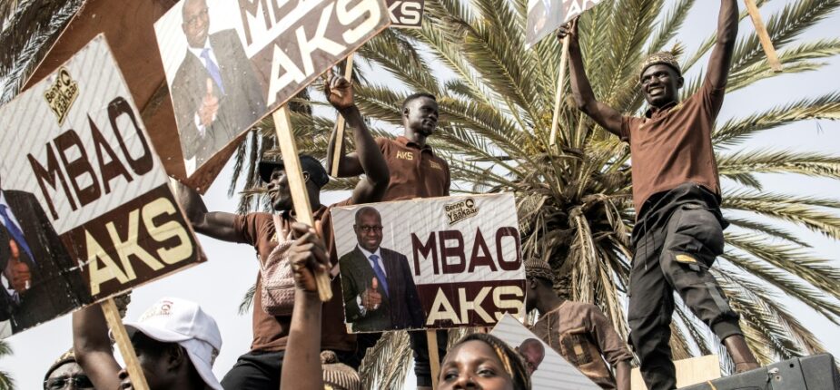Des partisans de la coalition du Président du Sénégal Macky Sall, Bennoo Bokk Yaakaar, portent des pancartes de leurs candidats lors de leur dernier meeting de campagne à Dakar le 29 juillet 2022.