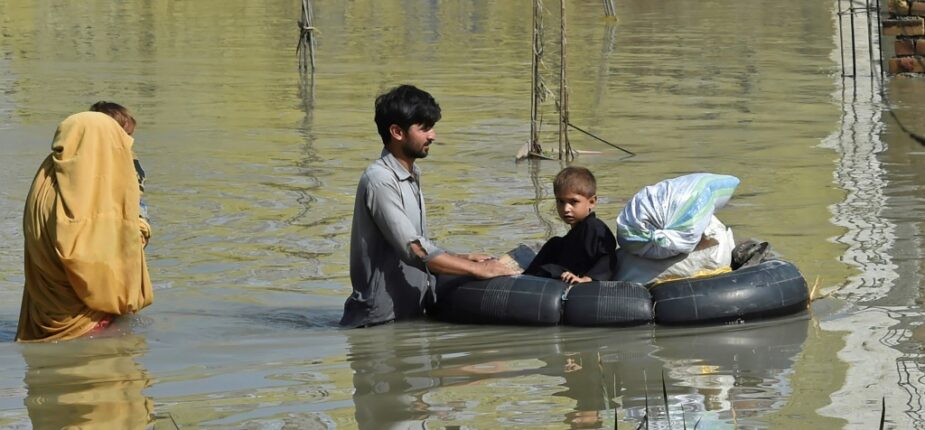 Une famille dans une zone inondée par les pluies de mousson, le 29 août 2022 à Charsadda, au Pakistan