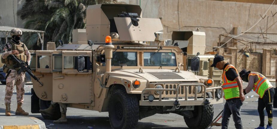 Des soldats montent la garde à l'entrée de la Zone verte pendant que des employés municipaux nettoient les rues après le retrait des partisans du leader chiite Moqtada Sadr, le 30 août 2022 à Bagdad, en Irak