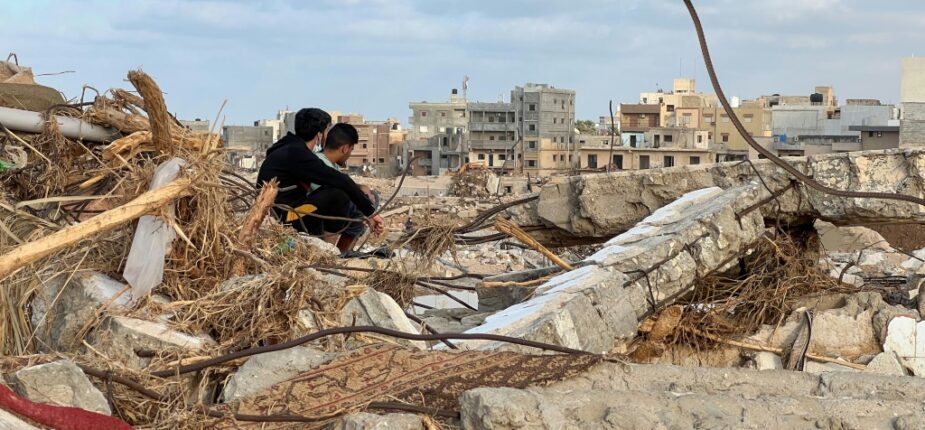 Des habitants assis au milieu des décombres de bâtiments à Derna, le 20 septembre 2023 en Libye